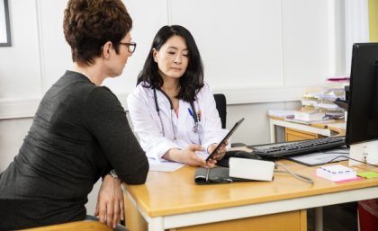 Doctor showing woman website on digital device.